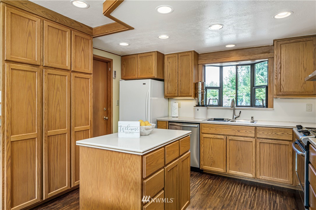 18003 Rhodes Lake Road East Bonney Lake, WA 98391 - Photo 5 of 40 a kitchen with a refrigerator a sink and dishwasher with wooden cabinets