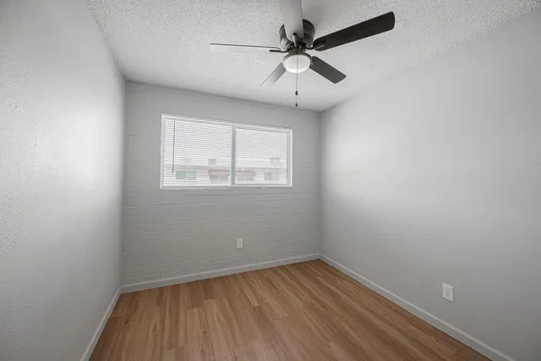 an empty room with a window and a ceiling fan