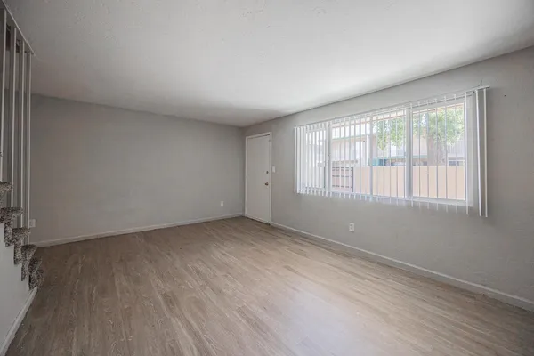an empty room with wooden floor and windows