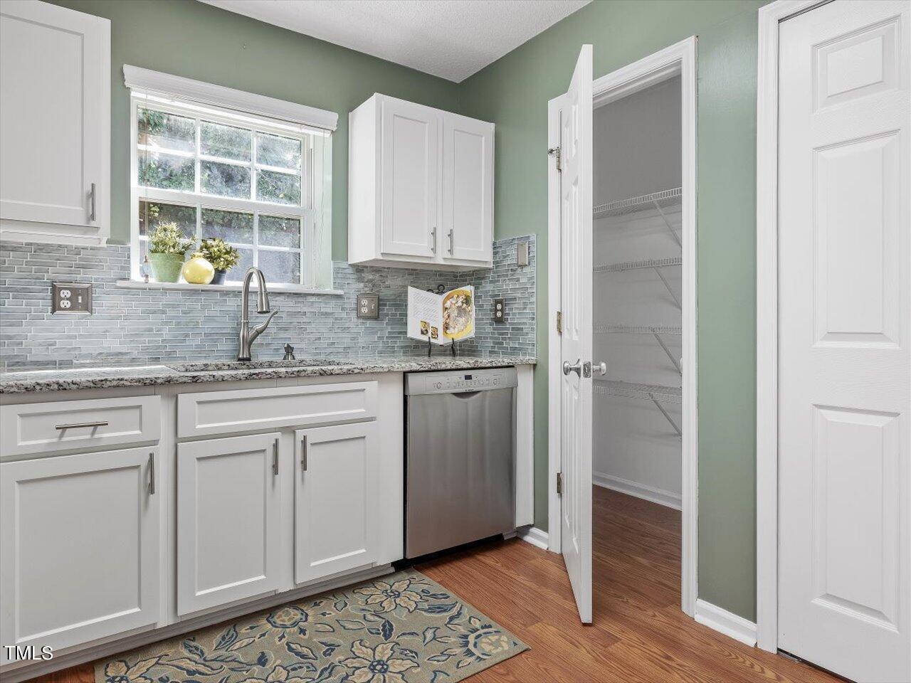 4509 Dolwick Drive Durham, NC 27713 - Photo 11 of 31 a kitchen with stainless steel appliances granite countertop a sink and cabinets with wooden floor