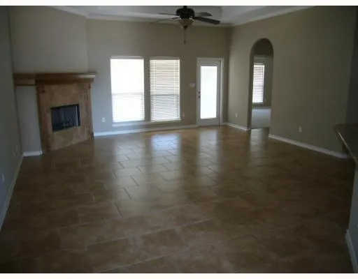 a view of an empty room with wooden floor and a fireplace