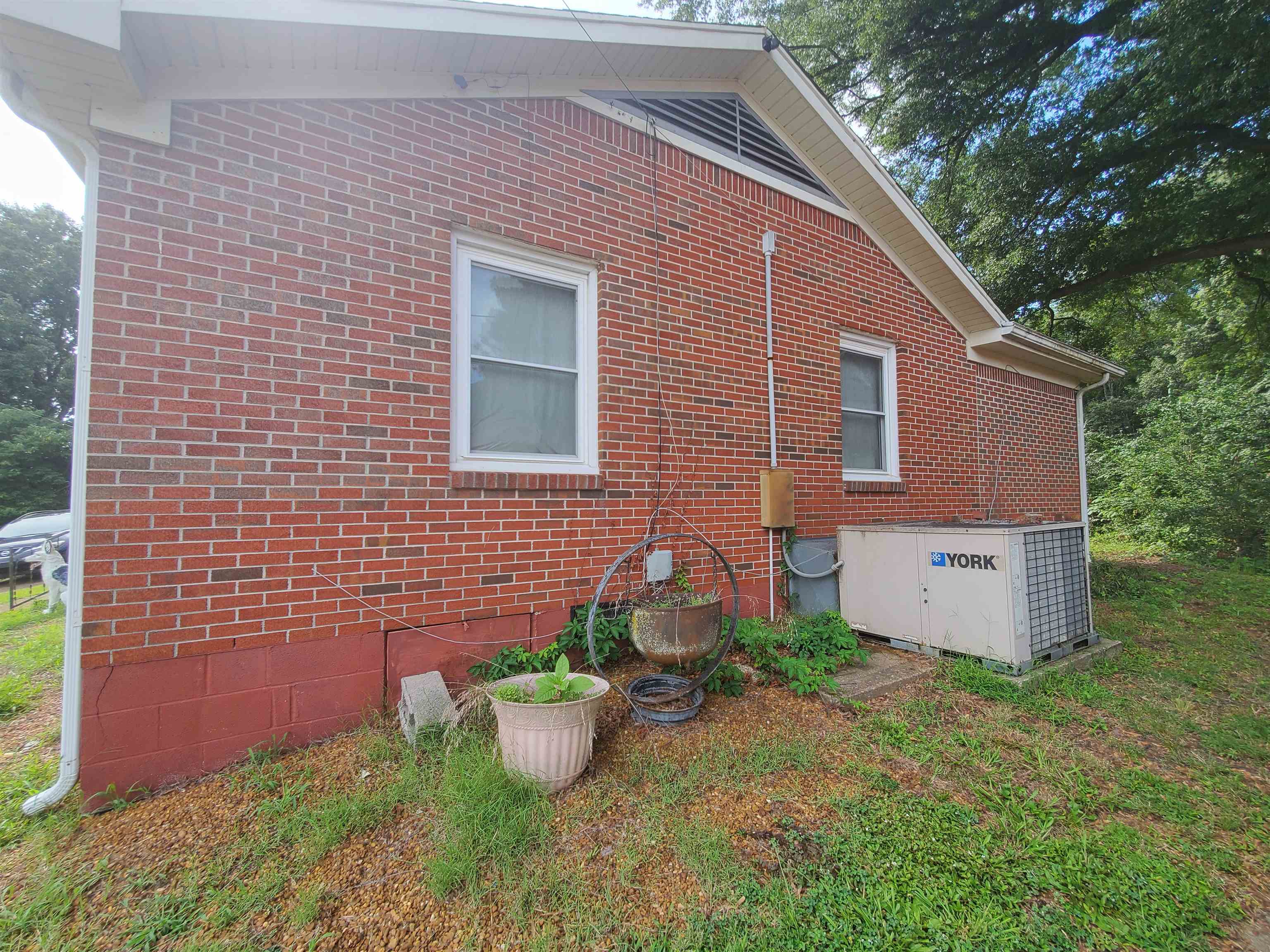 147 Rogers Street Sharon, TN 38255 - Photo 5 of 16 Brick exterior with white-framed windows, a white rain gutter system, and a prominent YORK HVAC unit