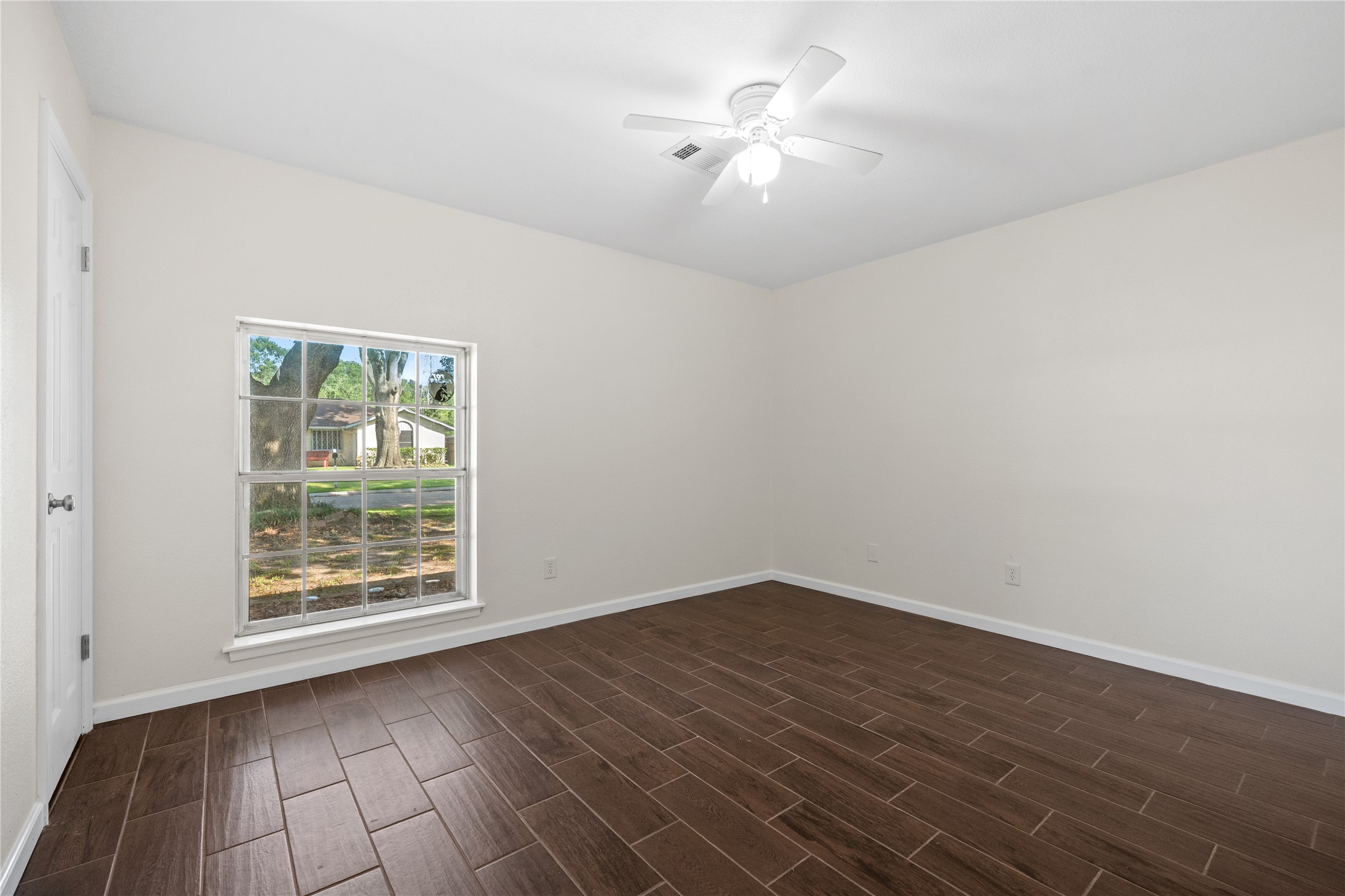 3930 Tumbleweed Lane Baytown, TX 77521 - Photo 19 of 23 an empty room with wooden floor chandelier fan and windows
