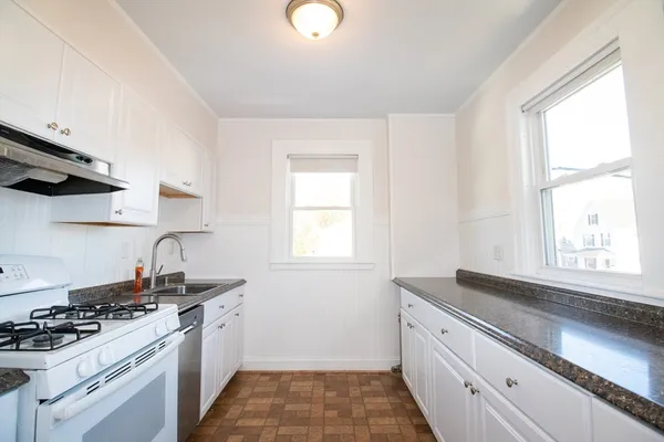 a kitchen with granite countertop a sink stove and cabinets