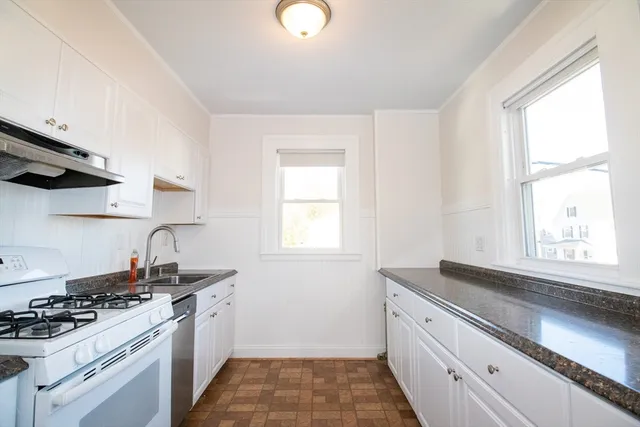 a kitchen with granite countertop a sink stove and cabinets