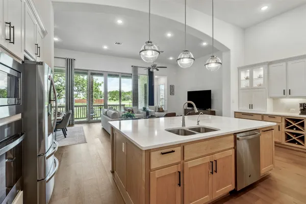 a kitchen with stainless steel appliances granite countertop a sink a stove and a large window with wooden floor