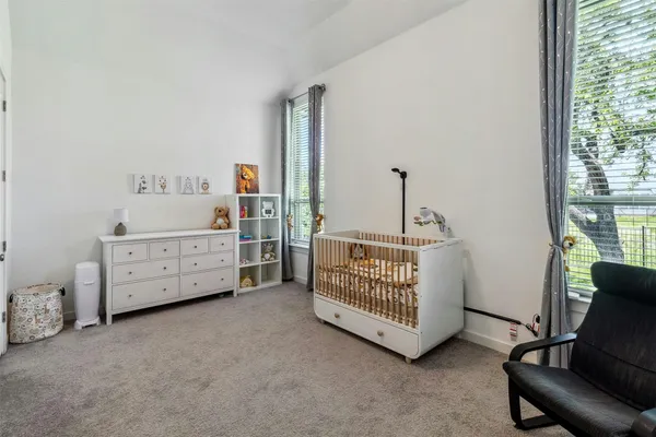 a room with a baby bed a couch and dresser