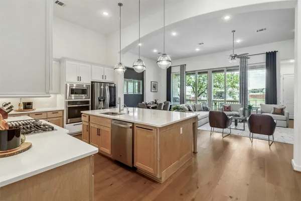 a kitchen with stainless steel appliances granite countertop a stove top oven a sink dishwasher a dining table and chairs with wooden floor