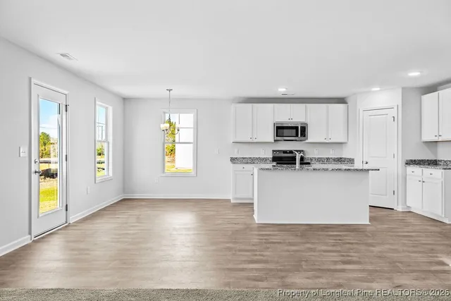 a kitchen with stainless steel appliances granite countertop a stove a sink and a microwave