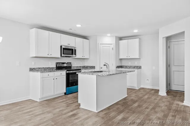 a kitchen with granite countertop white cabinets and stainless steel appliances