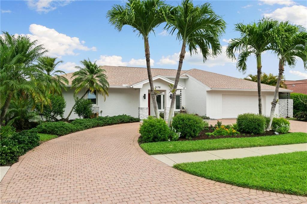 2178 Pinewoods Circle, Unit 25 Naples, FL 34105 - Photo 2 of 45 a front view of a house with garden and trees