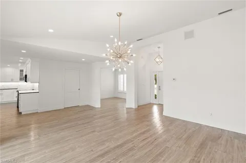 a view of an empty room with wooden floor and a chandelier