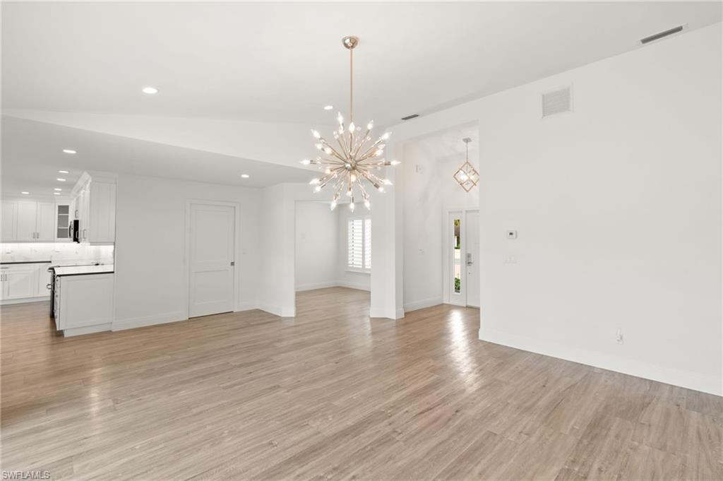 2178 Pinewoods Circle, Unit 25 Naples, FL 34105 - Photo 8 of 45 a view of an empty room with wooden floor and a chandelier