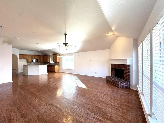 an empty room with wooden floor fireplace and windows