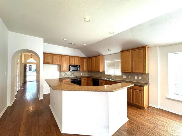 a kitchen with stainless steel appliances granite countertop a sink a stove and a refrigerator
