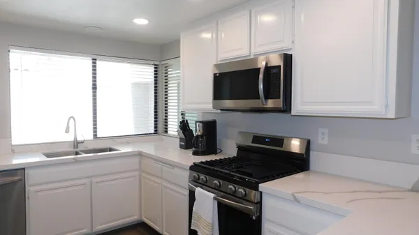 a kitchen with stainless steel appliances granite countertop a sink stove and microwave