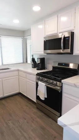a kitchen with stainless steel appliances a stove a microwave a sink and white cabinets