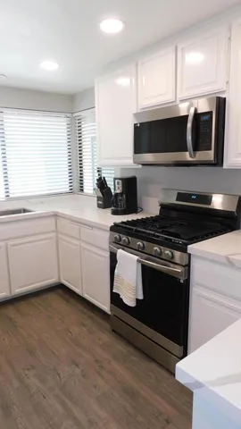 a kitchen with stainless steel appliances a stove a microwave a sink and white cabinets