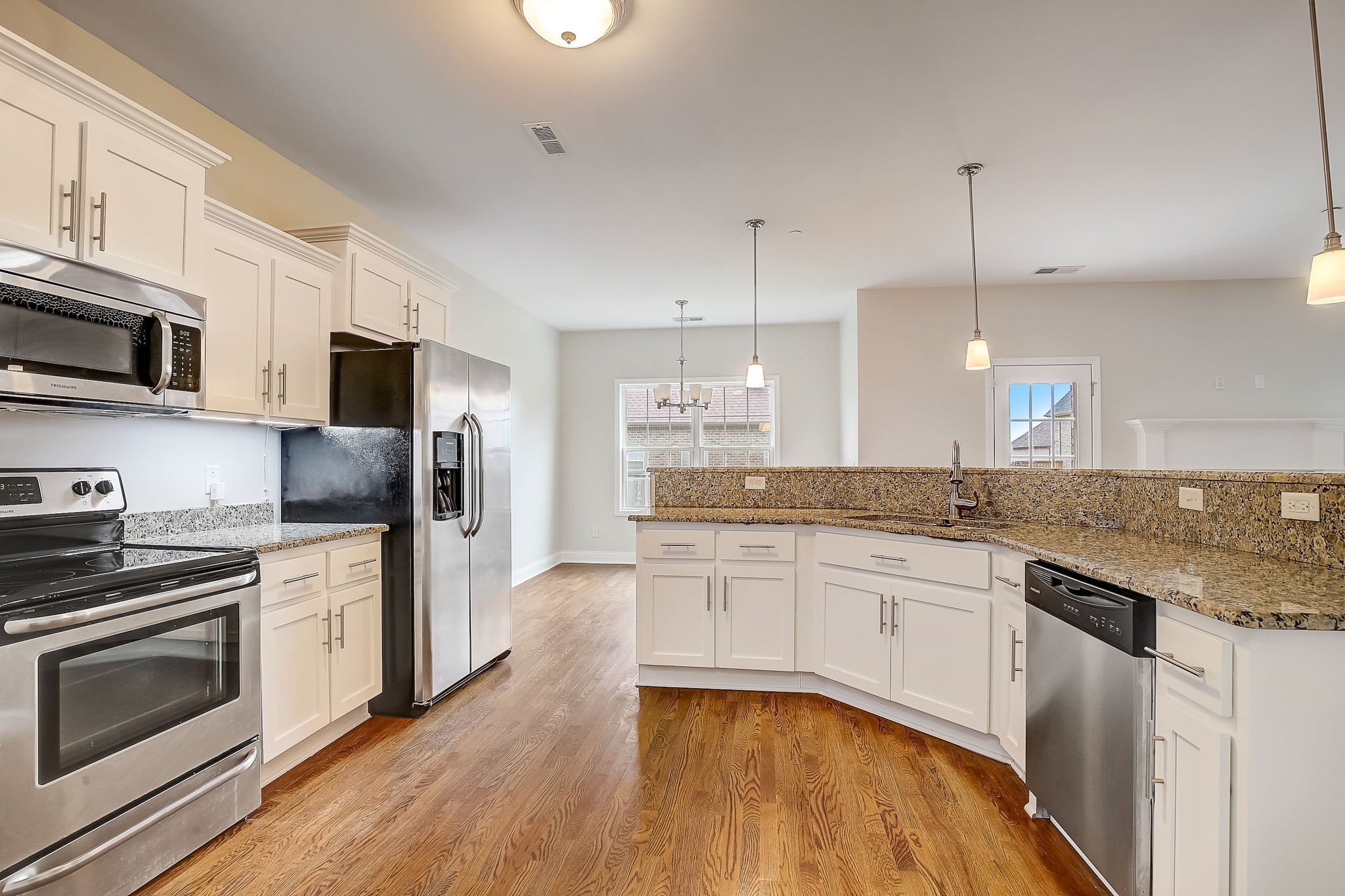 1028 Grace Road Pleasant View, TN 37015 - Photo 9 of 21 a large kitchen with stainless steel appliances granite countertop a stove top oven a sink dishwasher a refrigerator and a dining table with wooden floor