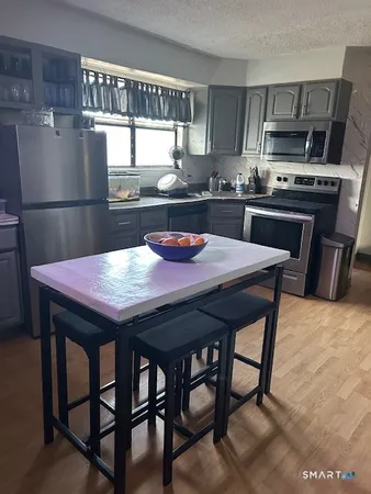 a kitchen with stainless steel appliances granite countertop a dining table chairs and a refrigerator