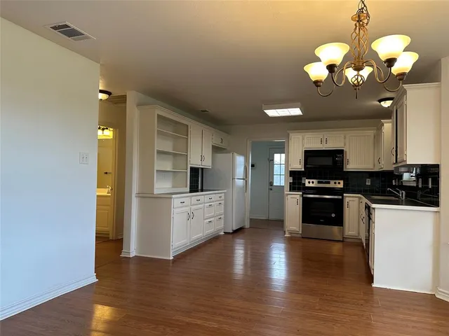a view of a livingroom with a fireplace wooden floor and chandelier