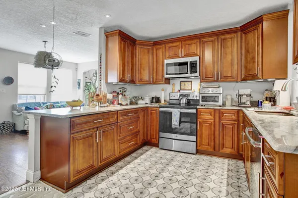 a kitchen with stainless steel appliances granite countertop a stove a sink dishwasher and a microwave oven with white cabinets