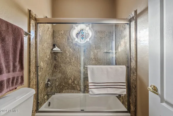 a bathroom with a granite countertop sink a toilet a mirror and shower