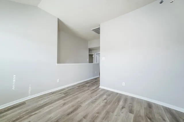 a view of an empty room with a ceiling fan and wooden floor