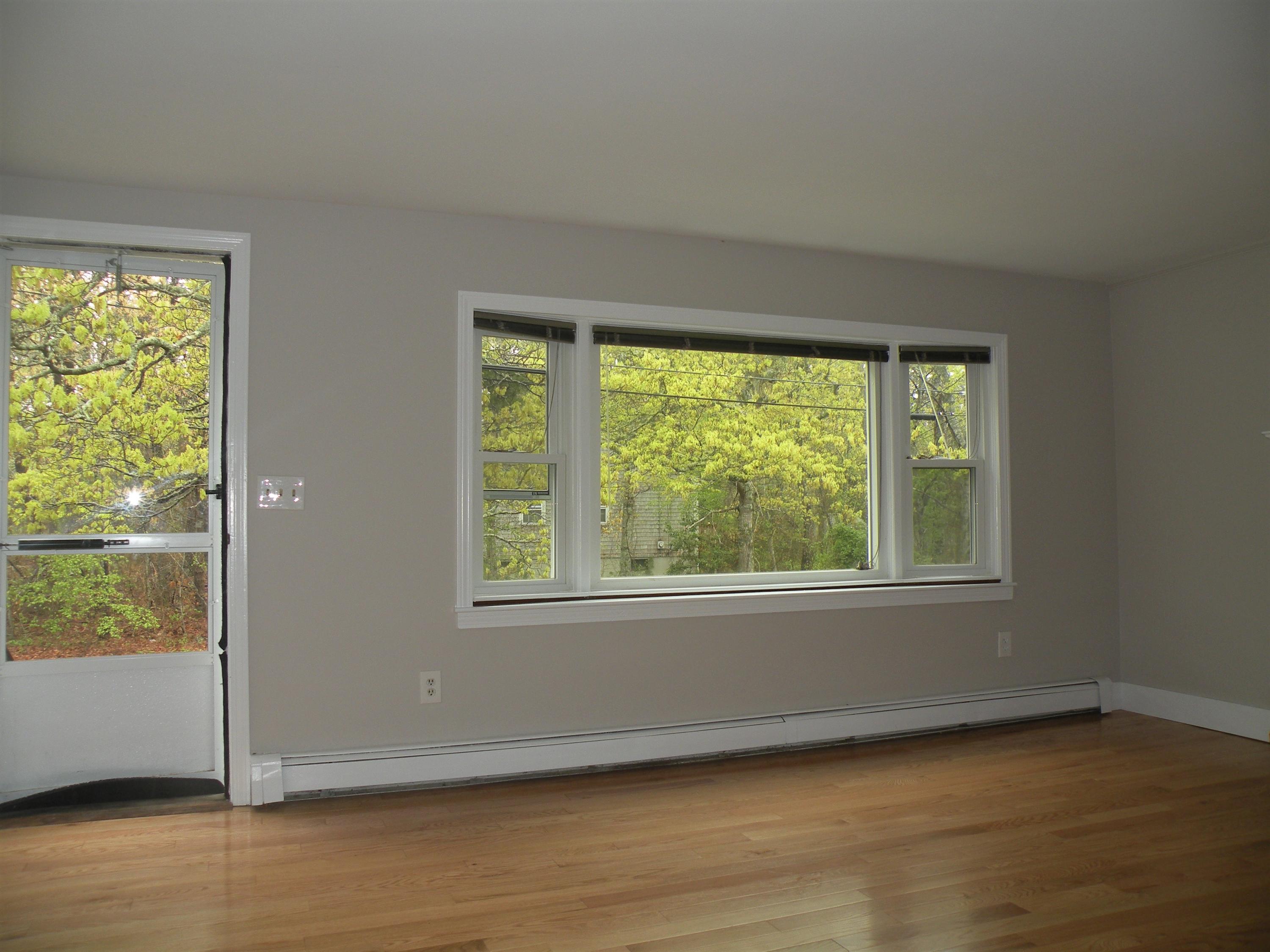 153 Harbor Hills Road Centerville, MA 02632 - Photo 5 of 18 an empty room with wooden floor and windows