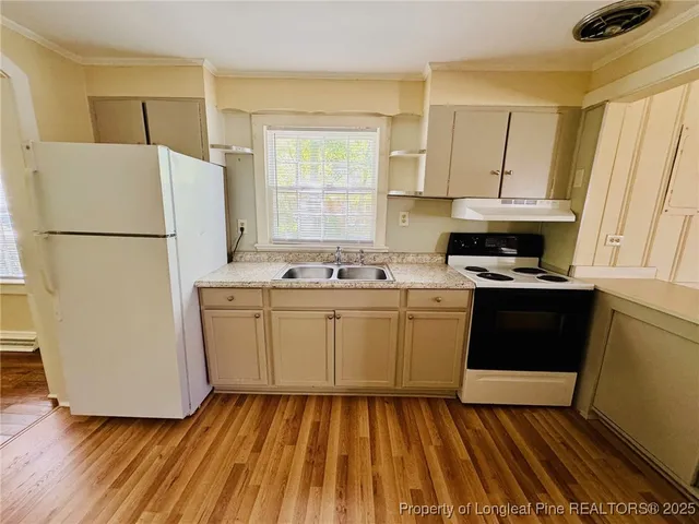 a kitchen with sink a refrigerator and white cabinets