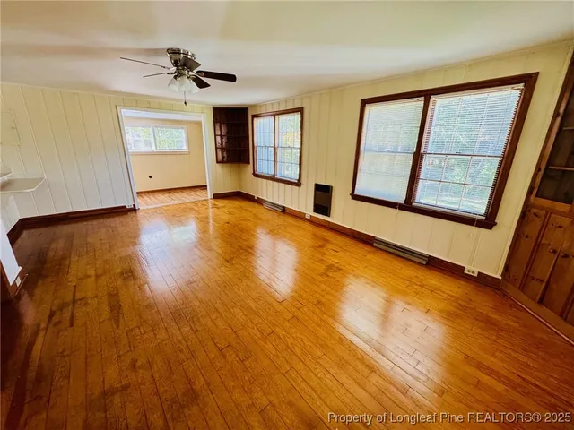 a view of an empty room with a window and wooden floor