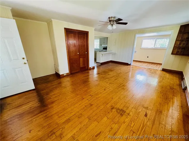 an empty room with wooden floor and a ceiling fan