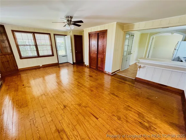 a view of an empty room with a window and wooden floor