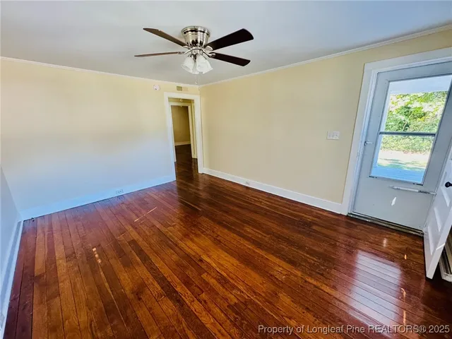a view of an empty room with wooden floor and a window
