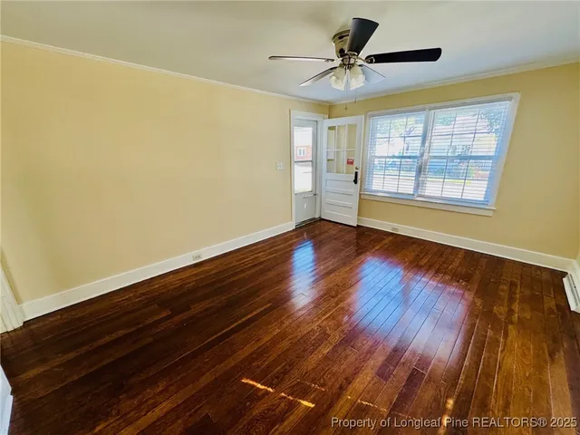 a view of an empty room with a window and wooden floor