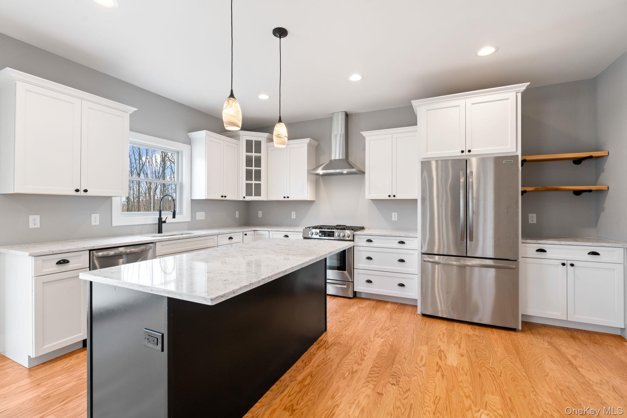 13 Harrier Ridge Drive Wallkill, NY 12589 - Photo 2 of 40 Kitchen with stainless steel appliances, glass insert cabinets, wall chimney range hood, white cabinetry, and hanging light fixtures