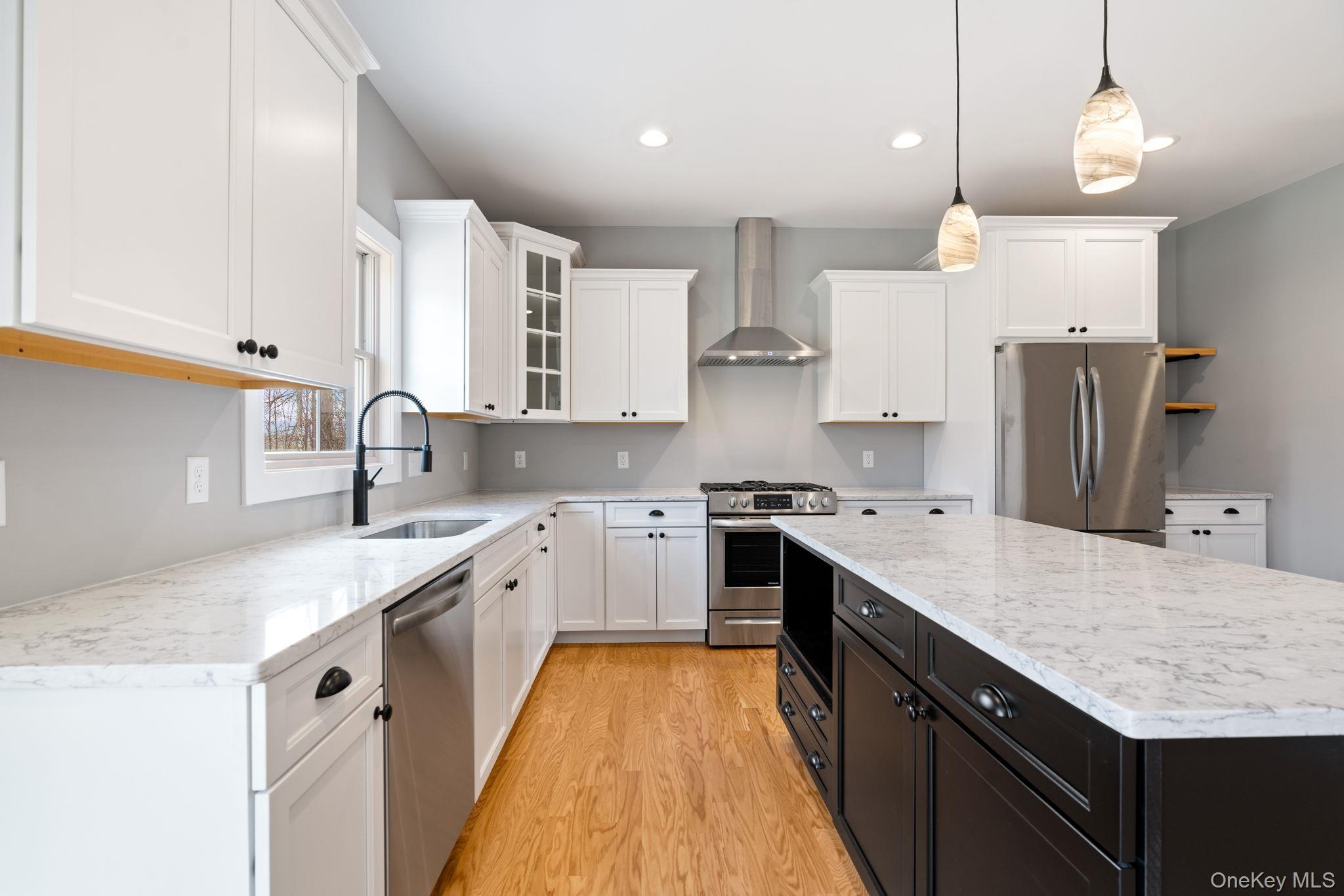 13 Harrier Ridge Drive Wallkill, NY 12589 - Photo 3 of 40 Kitchen with glass insert cabinets, white cabinets, stainless steel appliances, wall chimney range hood, and pendant lighting