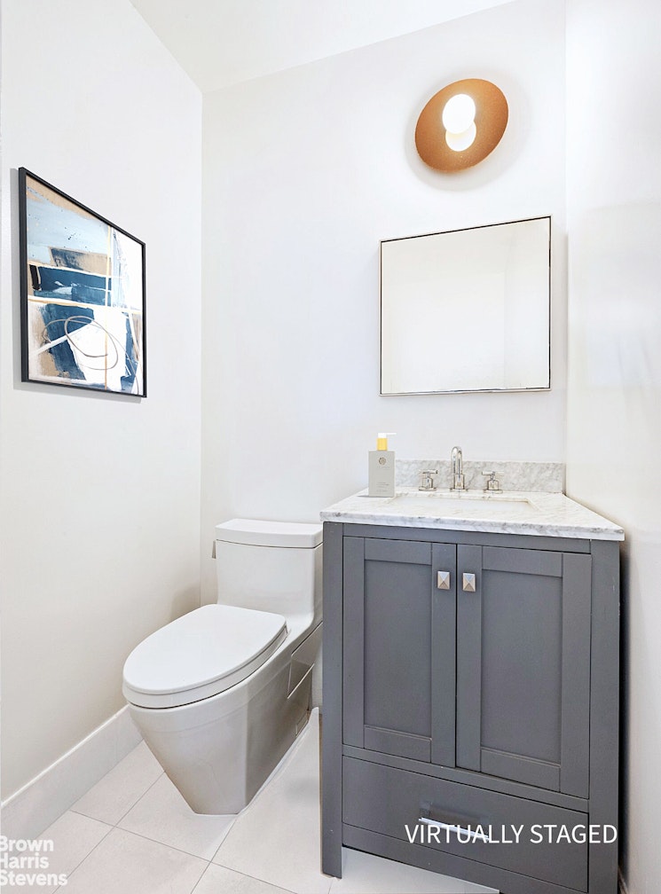 240 East 47th Street, Unit 39AB Manhattan, NY 10017 - Photo 6 of 22 a bathroom with a toilet sink vanity and mirror