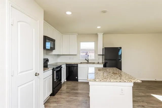 a kitchen with a stove top oven a sink a refrigerator and white cabinets