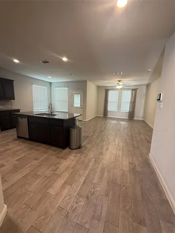 a view of kitchen and empty room with wooden floor