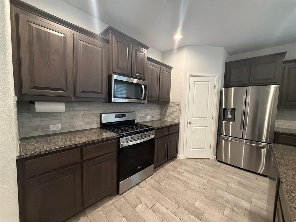 1110 Pacifica Trail Cleburne, TX 76033 - Photo 4 of 24 a kitchen with granite countertop wooden cabinets a refrigerator and a sink