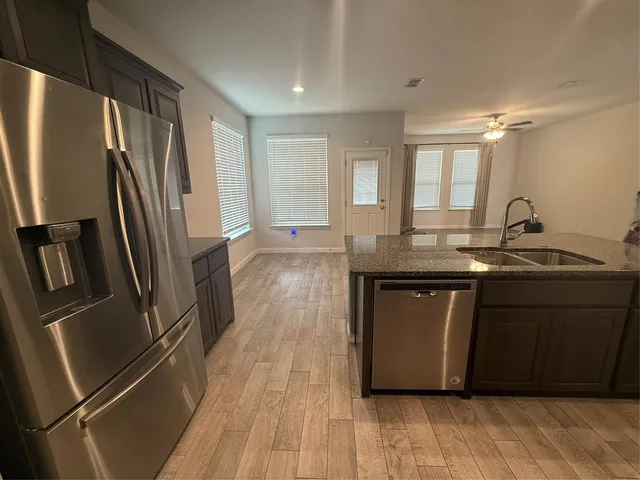 a kitchen with granite countertop a refrigerator sink and wooden floor