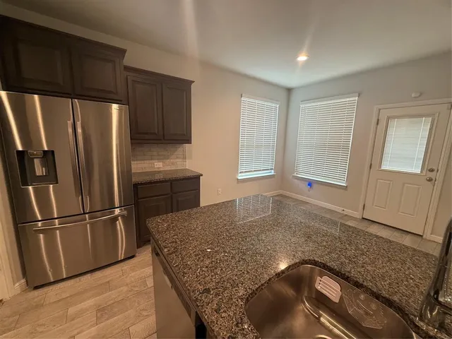 a kitchen with granite countertop a refrigerator and a sink
