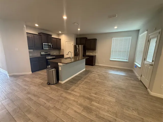 a kitchen with stainless steel appliances granite countertop a refrigerator and a stove top oven