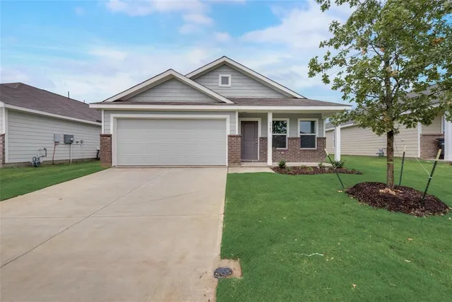 a front view of a house with a garden and trees