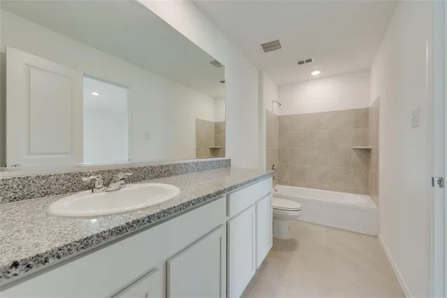 a bathroom with a granite countertop sink a toilet a mirror and bathtub