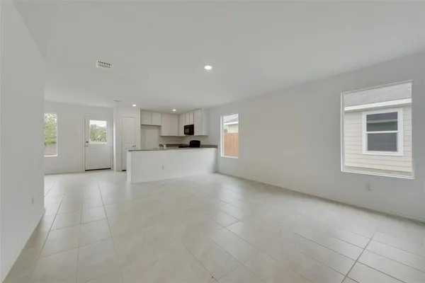 a view of empty room with kitchen and window