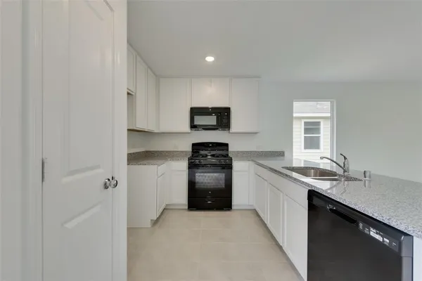 a kitchen with granite countertop stainless steel appliances a sink stove and refrigerator