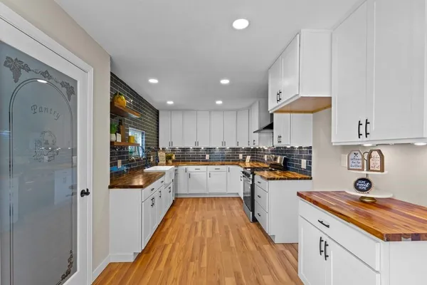 a large kitchen with stainless steel appliances granite countertop a lot of counter space and wooden floor