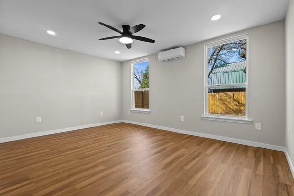 a view of an empty room with wooden floor and a window